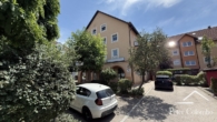 Aussenansicht mit Parkplätzen - Top gepflegte 3-Zimmer-Wohnung im 1. OG mit Südbalkon & Blick ins Grüne, TG-Stellplatz inklusive